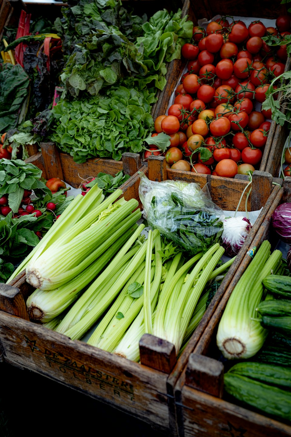Fresh vegetables in rustic wooden crates at an outdoor market.