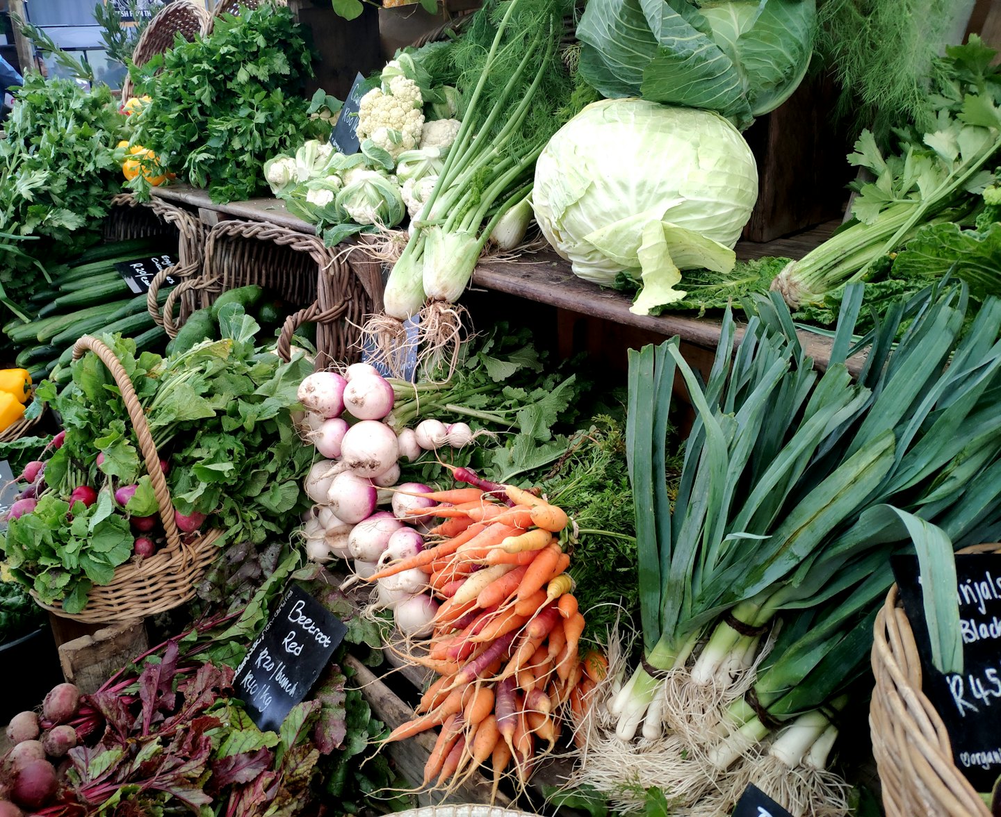 Fresh organic vegetables displayed on rustic wooden shelves at a market.